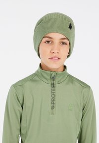 Berretto a maglia verde con texture a coste e piccolo logo tag, abbinato a un top a maniche lunghe coordinato con mezza cerniera e stampa del logo.