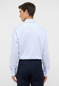 Lichtblauwe en witte gestreepte overhemd met lange mouwen en een button-down kraag. Bevat knopen bij de manchetten en heeft een gladde stofstructuur. Marineblauwe broek zichtbaar.