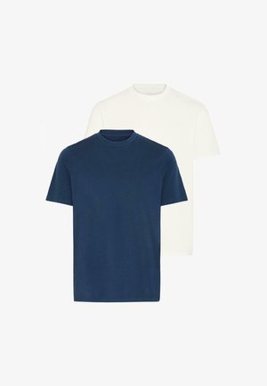 T-shirt en coton bleu marine à manches courtes, associé à un jean en denim bleu clair. Le modèle se tient avec une main dans la poche, portant des baskets grises.