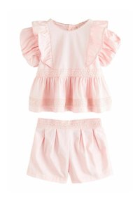 Ensemble deux pièces rose comprenant un haut à manches courtes avec volants et bord en dentelle, ainsi que des shorts assortis à la conception plissée et une taille en dentelle.