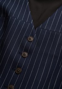 Granatowa tkanina w paski z dwoma brązowymi guzikami przy dekolcie w serek, o gładkiej fakturze i eleganckim, dopasowanym kroju.