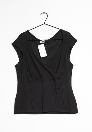 Blouse noire à manches courtes de style cache-cœur sur un cintre avec une étiquette de prix blanche rectangulaire attachée à l'encolure.