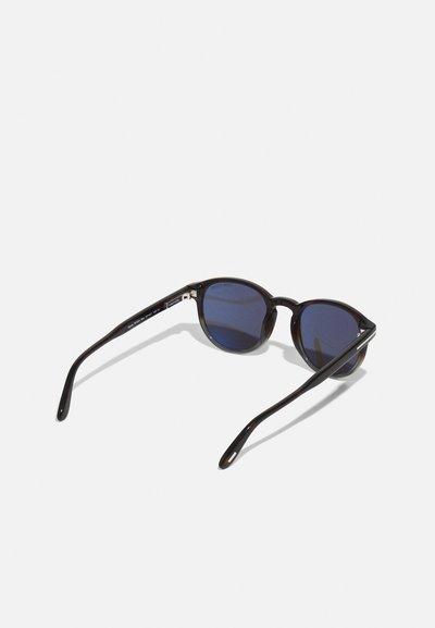 Schwarze Cat-Eye-Sonnenbrille mit blauen getönten Gläsern, schlanken Bügeln und einer glatten Oberfläche. Die markante Form steigert die visuelle Anziehungskraft.