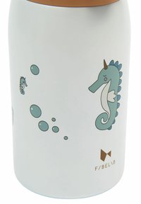 Botella blanca aislada con tapa marrón, con ilustraciones azules de caballitos de mar y burbujas, y un logotipo impreso en marrón.