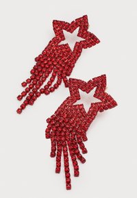 Červené náušnice v tvare hviezdy so štýlovým dizajnom, zdobené trblietavými červenými kamienkami, s strapcami zavesenými dole pre dodatočný pohyb.