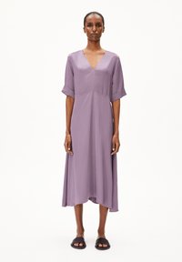 Lavender midi dress with a V-neck, short rolled sleeves, and a flared hem, made of lightweight fabric. Paired with flat black sandals.