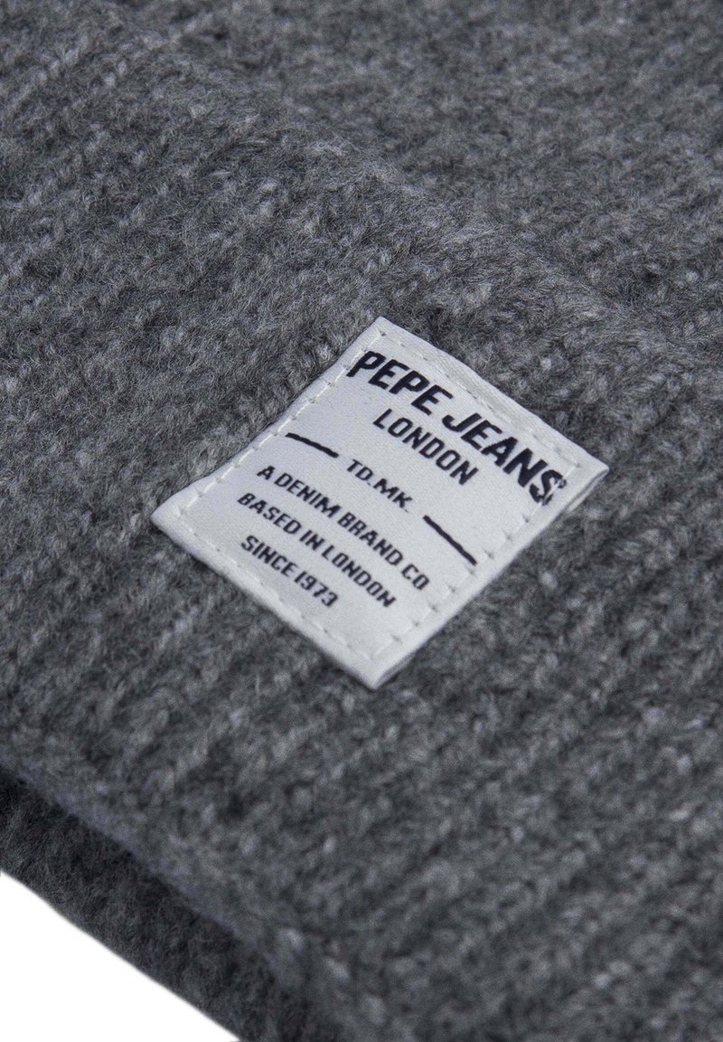 Tessuto grigio testurizzato con un motivo tessuto, caratterizzato da un'etichetta rettangolare bianca con testo nero che recita 'PEPE JEANS LONDON.'