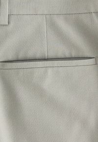 Hellgrauer Stoff mit glatter Textur, der ein flaches Taschendesign und subtile Nahtdetails aufweist, geeignet für formelle oder legere Kleidung.