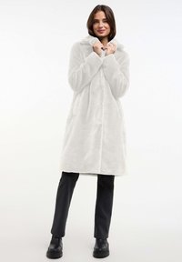 Fleece jas in lichtgrijs met een capuchon, voorzakken en een zachte textuur. Lange mouwen en een rechte snit die tot halverwege de dij reikt.