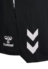 Camiseta deportiva negra hecha de tela texturada, con un logo blanco y un patrón de tres chevrons, dobladillo cosido y detalles de ventilación lateral.