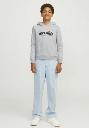 Grijze hoodie met logo aan de voorkant, trekkoord, ribgebreide manchetten en zoom, gecombineerd met lichtblauwe rechte jeans en witte sneakers.