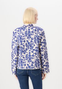 Floral-patterned jacket in blue on cream background, featuring long sleeves, a collar, and a slightly fitted design.