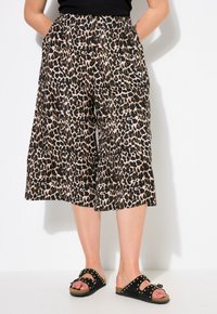 Leopardprint culottes van een lichte stof, met een zwart, bruin en tan patroon; gecombineerd met zwarte sandalen met gestifte accenten.