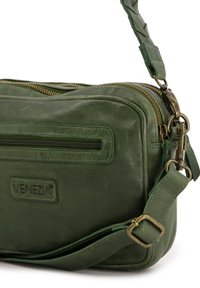 Grüne Leder-Crossbody-Tasche mit strukturiertem Finish, goldfarbenen Reißverschlüssen und einem geflochtenen Schulterriemen. Mit einer Vordertasche mit Reißverschluss.