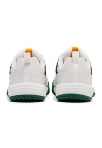 Vita atletiska sneakers med gröna gummisålar. Funktioner inkluderar en texturerad överdel, en kontrasterande orange hälskons samt en vadderad krage.