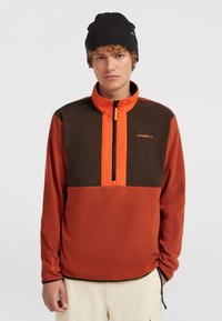 Fleece-Pullover in Rost, Braun und Orange mit hohem Kragen, Brustreißverschluss und Logodetail. Verfügt über eine glatte Textur und lange Ärmel.