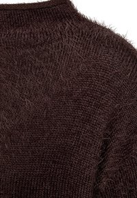 Brun stickad tröja med en fluffig textur, som har en rund halsringning och en lös passform, vilket framhäver ett mjukt och fransigt utseende.