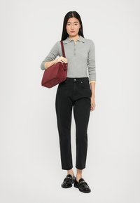 Polo gris à manches longues avec col jaune, pantalon noir taille haute, mocassins noirs et sac à main en suède bordeaux.
