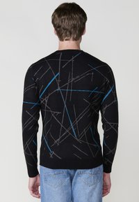 Suéter negro con un patrón geométrico en líneas grises y azules. Cuenta con puños y dobladillo acanalados, hecho de un material de punto suave.