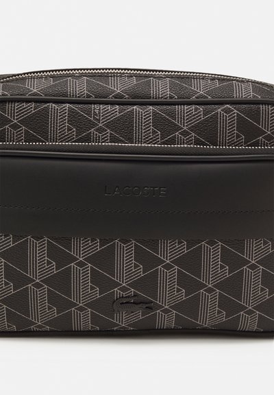 Sac en cuir noir avec un motif géométrique aux contours blancs, un accent noir lisse et un logo en relief sur le devant.