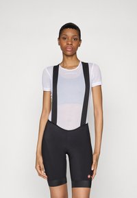 Black cycling shorts with a mesh white top, featuring black straps. The shorts have a padded seat area and a red logo on the leg.