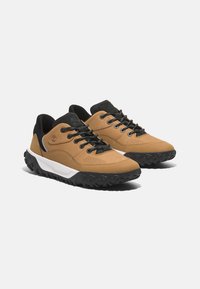Zapatillas de cuero marrón con detalles en negro, diseño perforado, suela de goma negra texturizada y entresuela blanca. Presentan cordones negros y detalle del logo.
