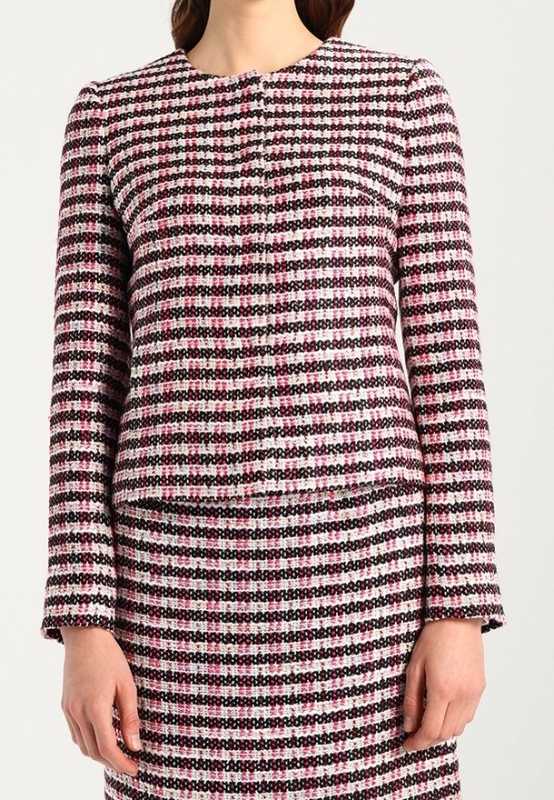 Veste en tweed tissé rose, noire et blanche avec un col rond, des manches longues et une fermeture à boutons, présentant un motif à carreaux texturé.