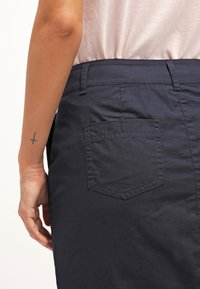 Pantaloni blu navy realizzati in cotone, dotati di una singola tasca posteriore di forma rettangolare e dettagli di cucitura minimi.