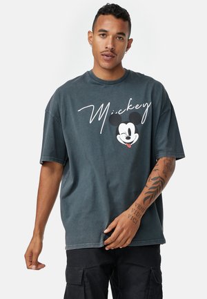 Mørk grå oversized t-shirt lavet af bomuld, med et hvidt "Mickey" tekstdesign og et trykt ansigt af Mickey Mouse på forsiden.
