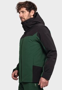 Grüne und schwarze wasserdichte Jacke mit Kapuze, die ein geometrisches Design aufweist, einen Reißverschluss auf der Vorderseite hat und zwei Seitentaschen besitzt.