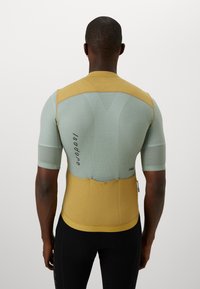 Camicia aderente a maniche corte di colore azzurro chiaro e giallo. Realizzata in tessuto strutturato e traspirante con finitura liscia e dettaglio del logo sul retro.