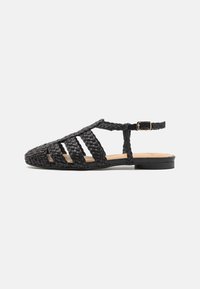 Svarte flettede skinn-sandaler med åpen tå-design, utskjæringer på siden og justerbar ankelstropp. Flat såle og minimal hardware.