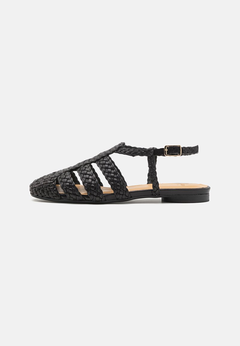 Svarte flettede skinn-sandaler med åpen tå-design, utskjæringer på siden og justerbar ankelstropp. Flat såle og minimal hardware.