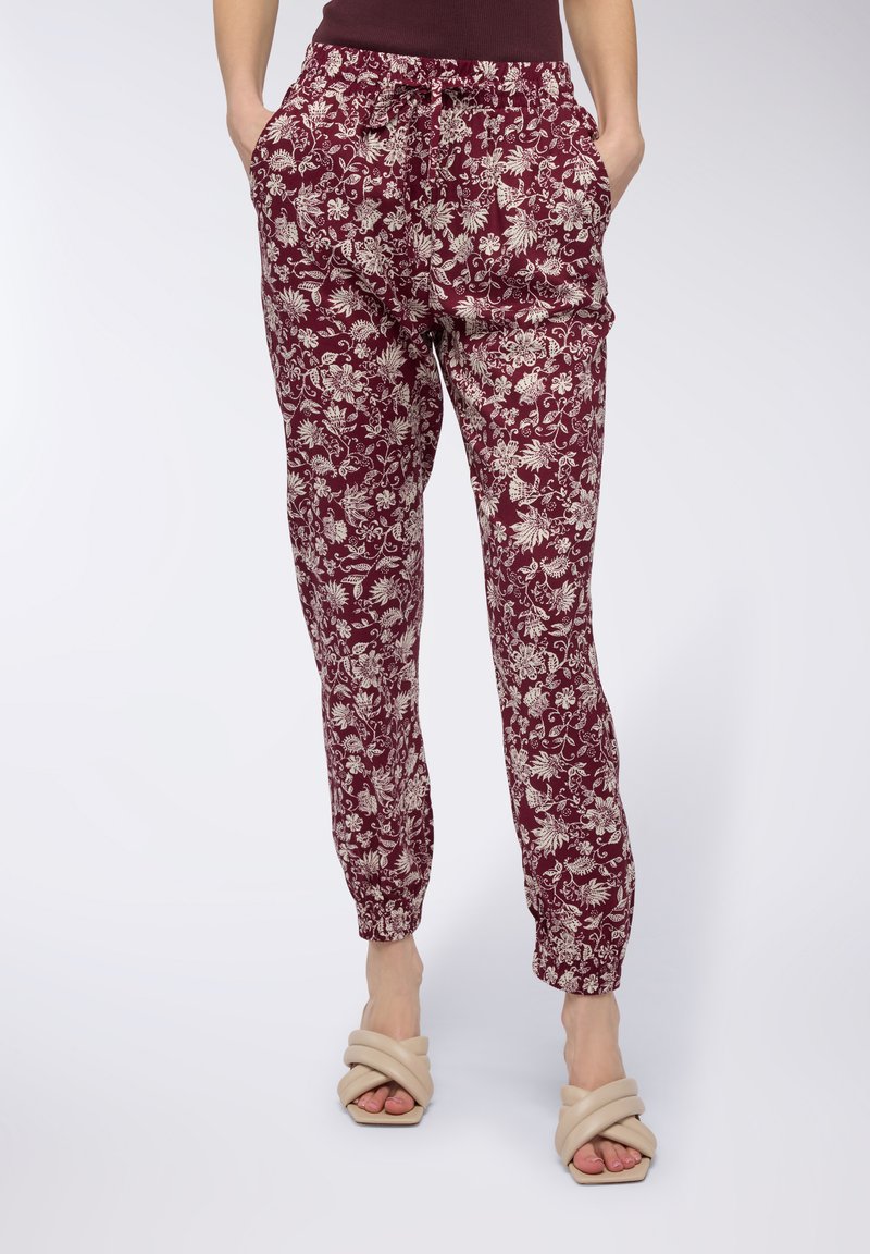 Pantaloni jogger bordeaux con stampa floreale in materiale leggero, dotati di vita elastica, coulisse e tasche laterali con polsini arricciati.