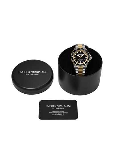 Montre Emporio Armani Sea Explorer avec un cadran noir et or, un bracelet métallique bicolore, un boîtier noir et une carte de certification pour une étanchéité jusqu'à 200 m.