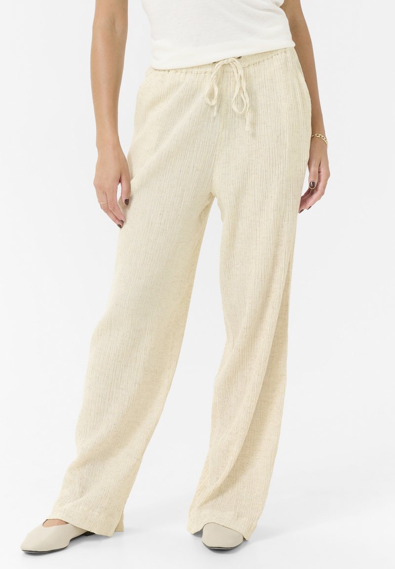 Pantalon large texturé de couleur crème, avec une taille élastique et un cordon de serrage. Fini lisse avec de légères rayures verticales.