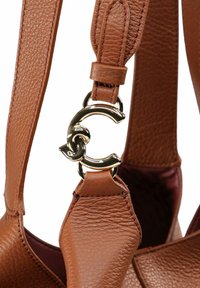 Tracolla di borsa in pelle marrone texturizzata con bordi cuciti e una chiusura in metallo dorato a forma di lettera C intrecciata.