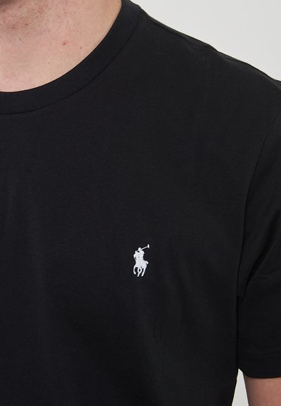 T-shirt in cotone nero con scollatura rotonda e maniche corte. Un piccolo logo ricamato bianco di un giocatore di polo si trova sul lato sinistro del petto.