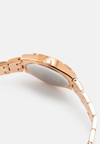 Orologio da polso in metallo rosa con cassa tondeggiante, corona testurizzata e bracciale a maglie. Quadrante chiaro con marcature ben visibili e logo del marchio.