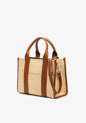 Bolso tote rectangular de paja tejida con asas, ribete, bolsillo frontal y correa ajustable para el hombro de cuero marrón con hebilla metálica.