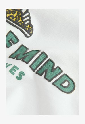 Tessuto bianco con scritte verdi in rilievo e contorni scuri, con una grafica di stampa leopardata in alto.