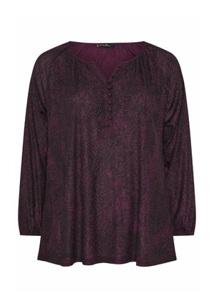 Długosleeve, fioletowa bluzka z teksturowanym, zwierzęcym wzorem. Posiada dekolt w kształcie litery V oraz cztery guziki na przodzie.