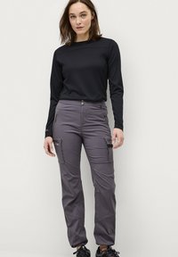 Graue Cargo-Hosen mit mehreren Taschen, einem Knopfverschluss und einer glatten Textur. Getragen mit einem langärmeligen schwarzen Oberteil.