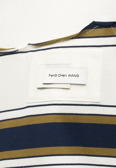 Ύφασμα με ρίγες σε μπλε ναυτικό, λευκό και μουσταρδί οριζόντιες γραμμές, με ραμμένη λευκή ορθογώνια ετικέτα ύφασμα με κείμενο.