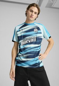 Blå og sort gradient sports trøje med korte ærmer, der har Olympique de Marseille-logoet og Puma-logoet, lavet af et let materiale.