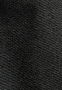 Tejido de mezclilla negro con una textura suave y un sutil patrón de tejido diagonal, presentando un tono uniforme en toda su extensión.