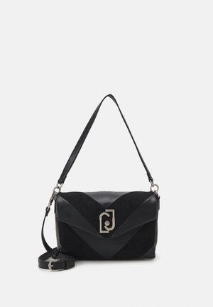 Sac à bandoulière en cuir noir avec rabat, fermoir argenté et une bandoulière réglable enroulée à côté sur un fond blanc.