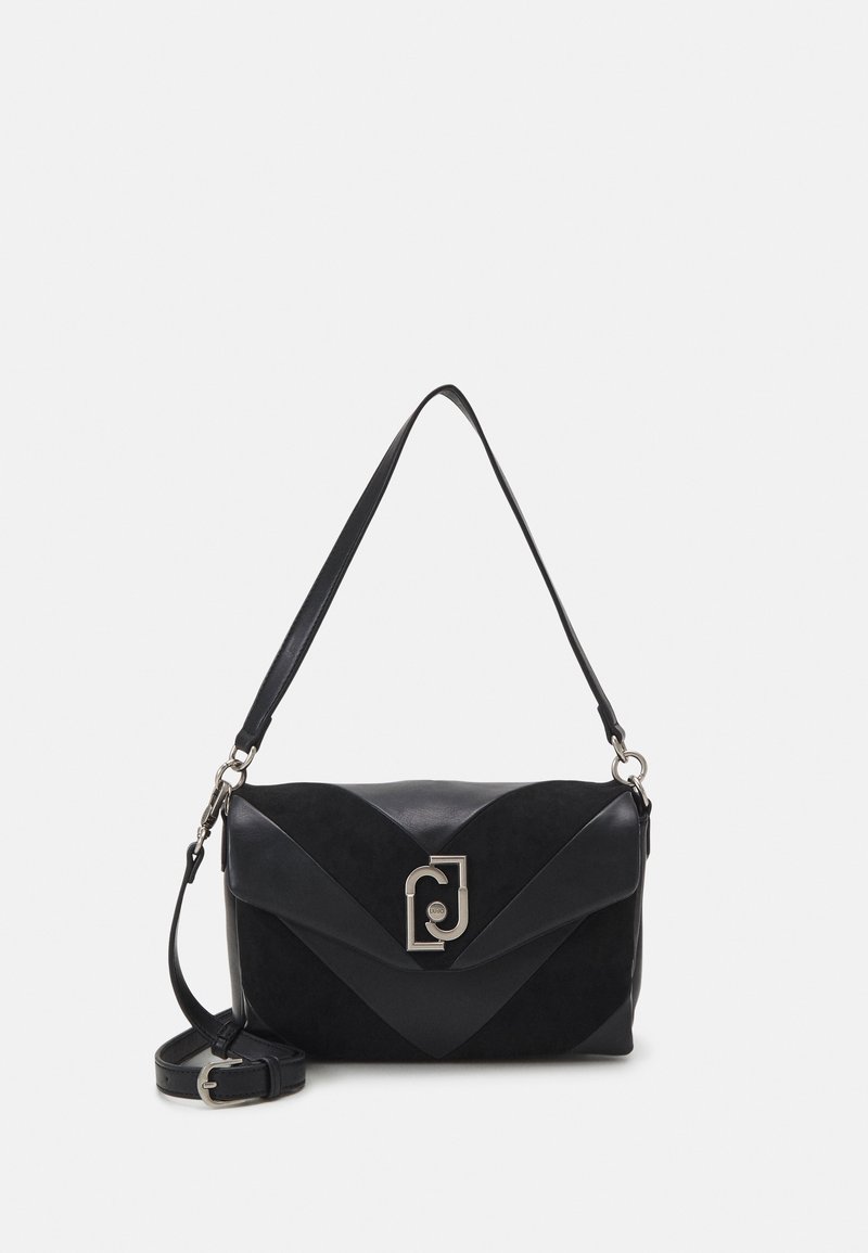 Sac à bandoulière en cuir noir avec rabat, fermoir argenté et une bandoulière réglable enroulée à côté sur un fond blanc.