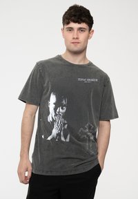 Gray cotton t-shirt featuring a black and white graphic of Tupac Shakur with distressed details and a cross design on the lower right.