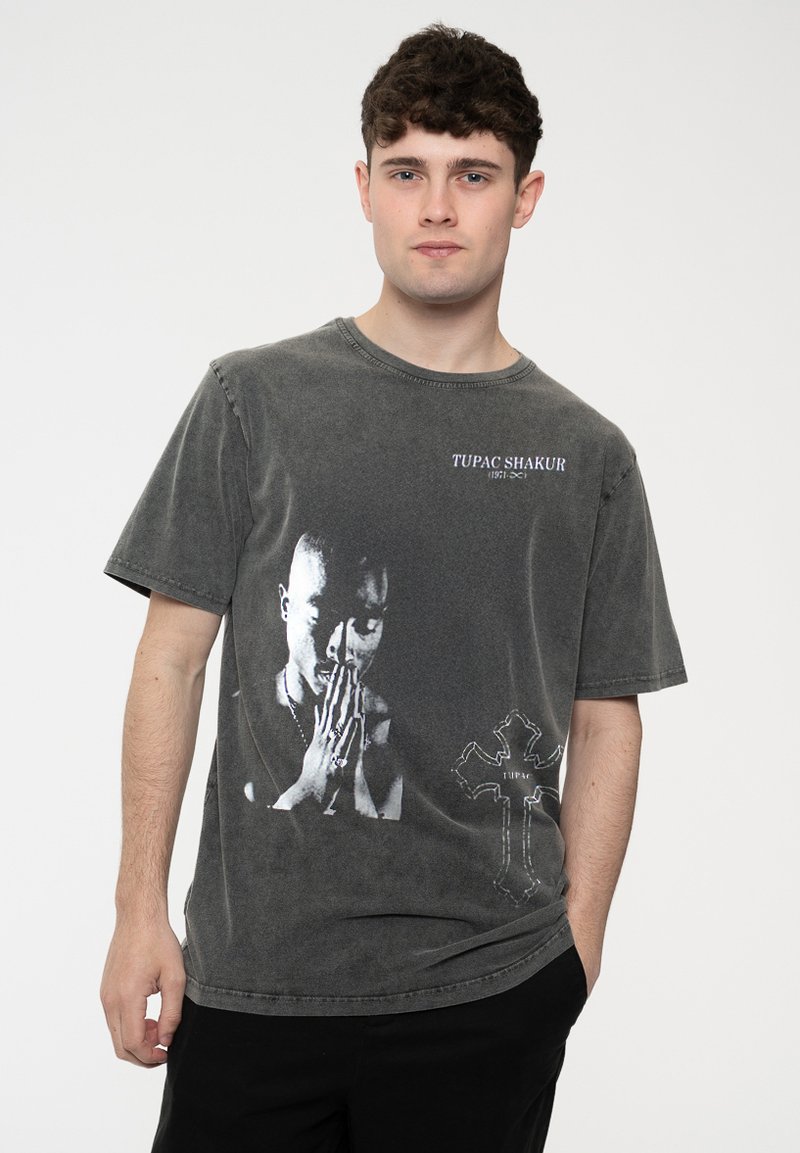 Gray cotton t-shirt featuring a black and white graphic of Tupac Shakur with distressed details and a cross design on the lower right.